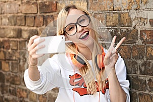 Young attractive blonde woman making selfie photo on smartphone.