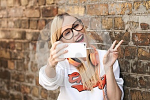 Young attractive blonde woman making selfie photo on smartphone.