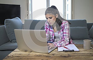 Young attractive and bored latin woman on her 30s working at home living room sitting on couch with laptop computer in stress look