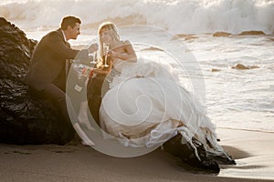 Young attractive bridal couple on beach with wine