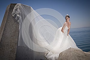 Young attractive bride in dress standing by concrete columns
