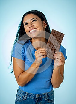 Young attractive brunette feeling joy and guilt at the thought of eating chocolate