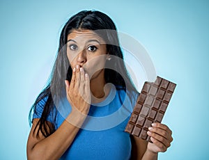 Young attractive brunette feeling joy and guilt at the thought of eating chocolate