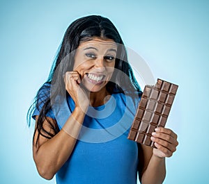 Young attractive brunette feeling joy and guilt at the thought of eating chocolate