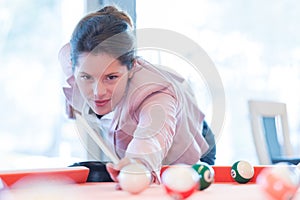 Young attractive brunette woman playing billiards pool game