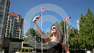 Young attractive brunette woman in a plaza in downtown Kelowna taking photos of a fountain. HD 24PS.