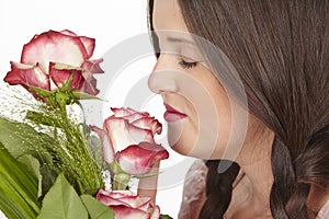 Young attractive brunette woman smells at roses