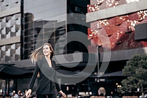 Young and attractive business girl on the background of the city in a beautiful black suit