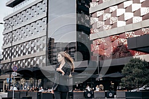 Young and attractive business girl on the background of the city in a beautiful black suit