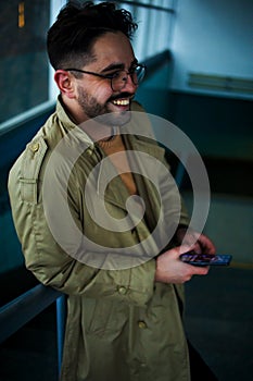 Young attractive business man in winter coat using smartphone in the underpass in city.