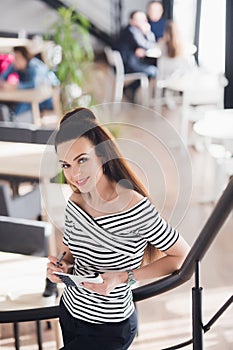 Young attractive business woman with long straight hair holds a notebook or job interview in a coffee-shop or cafe