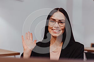 Young attractive business woman waving greeting at video conference on laptop online meeting