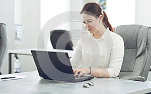 Young attractive business woman working in office smiling looking into laptop