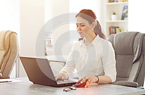 Young attractive business woman working in office smiling looking into laptop