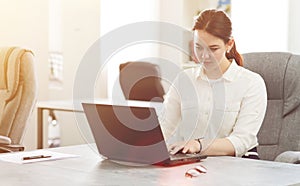 Young attractive business woman working in office smiling looking into laptop