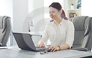 Young attractive business woman working in office smiling looking into laptop