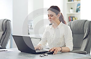 Young attractive business woman working in office smiling looking into laptop