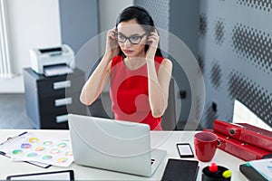 Young attractive businesslady in red dress and glasses sit at th