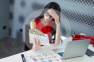 Young attractive businesslady in red dress and glasses sit at th