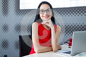 Young attractive businesslady in red dress and glasses sit at th