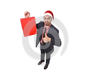 Young attractive businessman in Christmas Santa hat holding red shopping bag in December and New year sale