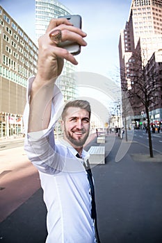 Young attractive businessman makes a selfie with a smartphone