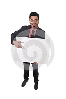 Young attractive businessman in suit and tie holding and pointing white blank billboard or advertising panel