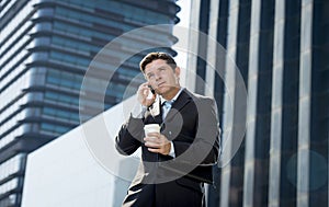 Young attractive businessman in suit and tie talking on mobile phone happy outdoors