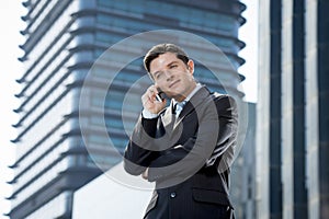 Young attractive businessman in suit and tie talking on mobile phone happy outdoors