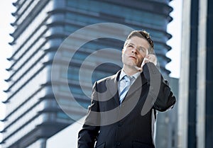 Young attractive businessman in suit and tie talking on mobile phone outdoors