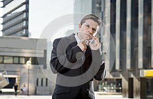 Young attractive businessman in suit and tie talking on mobile phone outdoors