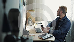 Young attractive businessman wearing glasses with yellow hair working at home. Using mobilephone sitting at the desk