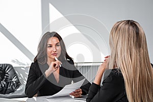 Young attractive businesswoman wearing formal suit is touching her chin