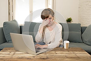 Young attractive and busy woman at home sofa couch doing some laptop computer work in stress looking worried in entrepreneur lifes