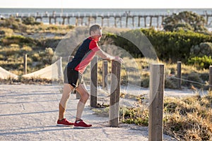 Young attractive Caucasian blond man on his 30s stretching leg i