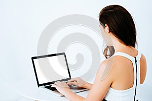 Young attractive Caucasian business woman working and typing on laptop on desk - with empty copy space on monitor screen in laptop