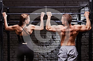 Young attractive caucasian crossfit man and woman working out in gym, rear view, couple