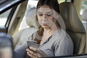 Young attractive caucasian woman behind the wheel driving a car with mobile phone in hand in traffic jam.