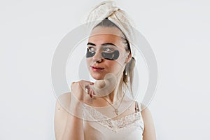 Young attractive Caucasian woman receive antiwrinkle therapy with black eye patches isolated on white photo