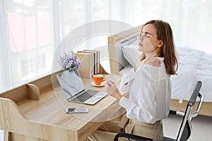 Young attractive caucasian woman wearing white casual clothes with computer and a cup of coffee. She sitting on working desk in