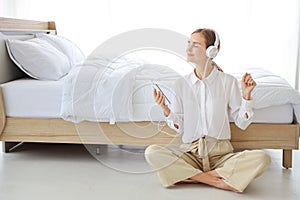 Young attractive caucasian woman wearing white casual clothes with headphone. She listening music or radio by using cell phone or