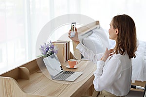 Young attractive caucasian woman wearing white casual clothes. She VDO call to her boyfriend by using cell phone in bedroom