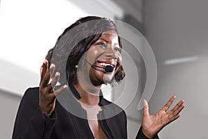 Young attractive and confident black African American business woman with headset speaking in auditorium at corporate training