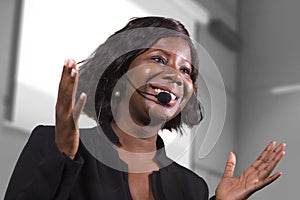 Young attractive and confident black African American business woman with headset speaking in auditorium at corporate training