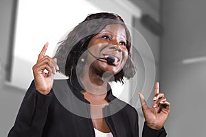 Young attractive and confident black African American business woman with headset speaking in auditorium at corporate training