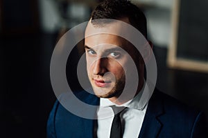 Young attractive and confident businessman in blue suit and black tie.