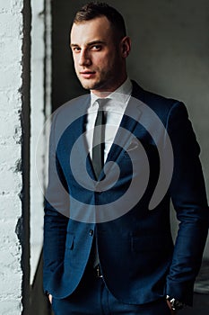 Young attractive and confident businessman in blue suit and black tie.