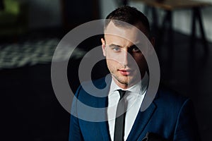 Young attractive and confident businessman in blue suit and black tie.