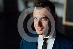 Young attractive and confident businessman in blue suit and black tie.