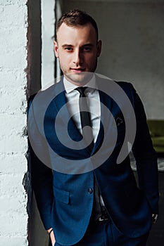 Young attractive and confident businessman in blue suit and black tie.